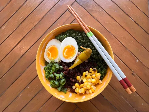 A bowl of tonkotsu ramen with chashu pork, soft-boiled egg, and green onions